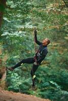 Up ,on, the rope, hanging,. Man ,is doing climbing in the forest by use of safety equipment photo