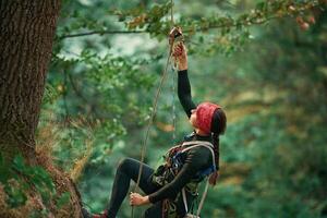 Woman ,is, doing climbing in the forest by the use of safety equipment photo
