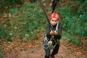 Front view. Woman, is doing climbing in the forest by the use of safety equipment photo