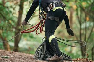 Close up, particle view. Man is doing climbing in the forest by use of safety equipment photo