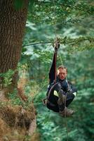 Activity, hanging on a rope. Man is doing climbing in the forest by use of safety equipment photo