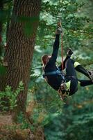 Activity, hanging, on a rope. Man is doing climbing in the forest by use of safety equipment photo