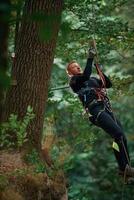 Activity, hanging on a rope. Man, is doing climbing in the forest by use of safety equipment photo