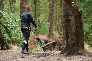 Process of preparing. Man ,is doing climbing in the forest by use of safety equipment photo