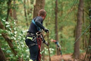 Process of preparing. Man ,is ,doing climbing in the forest by use of safety equipment photo