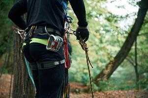 Close, up, particle view. Man is doing climbing in the forest by use of safety equipment photo