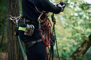 Close up particle, view. Man is doing climbing in the forest by use of safety equipment photo