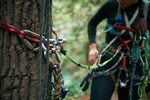 Close, up particle view. Man is doing climbing in the forest by use of safety equipment photo