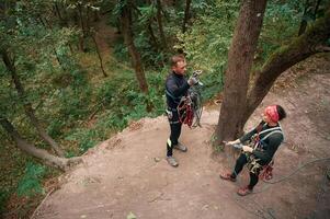 Top view... Man and woman doing climbing in forest with use of safety equipment photo