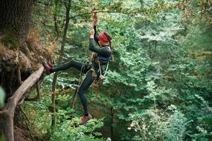 Focused, on, the climbing up.. Woman is in the forest, using the safety equipment photo