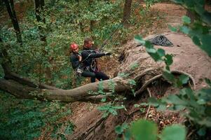 Going, down. Man and woman doing climbing in forest with use of safety equipment photo