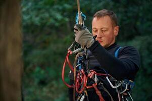 Man,, is doing climbing in the forest by use of safety equipment photo