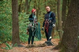 Man and ,woman doing climbing in forest with use of safety equipment photo