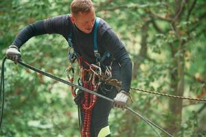 Extreme, sports, high,, up. Man is doing climbing in the forest by use of safety equipment photo