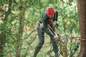 Woman ,is doing climbing in the forest by the use of safety equipment photo