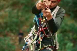 Front ,view. Woman is doing climbing in the forest by the use of safety equipment photo