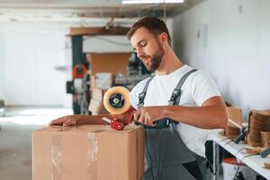 Packing, the, product. Handsome man is working at the factory of creating eco boxes photo
