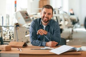 Positive, facial, expression. Handsome man is working at the factory of creating eco boxes photo