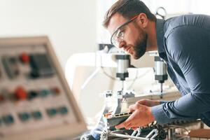 Operating, the machine... Handsome man is working at the factory of creating eco boxes photo