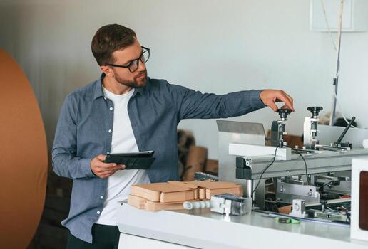 Front,, view. Handsome man is working at the factory of creating eco boxes photo