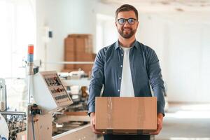 In ,,the, glasses. Handsome man is working at the factory of creating eco boxes photo