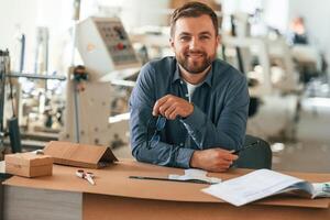 Positive, facial, expression. Handsome, man is working at the factory of creating eco boxes photo