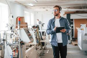 Smart engineer... Handsome man is working at the factory of creating eco boxes photo