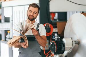Smart, engineer. Handsome man is working at the factory of creating eco boxes photo
