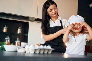 Front view. Mother with her, daughter, are, preparing food on the kitchen photo