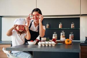 Playing with slices, of pepper. Mother ,with her daughter are preparing food on the kitchen photo