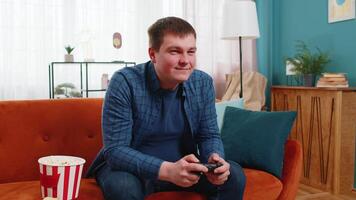 Man using joystick controller playing console online game fun enjoying sitting on home sofa video
