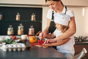 Side, view. Mother, with, her daughter are preparing food on the kitchen photo