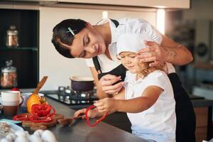 Side, view. Mother, with her daughter are preparing food on the kitchen photo