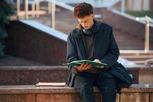 Young ,student,, is outside the university, in black clothes photo