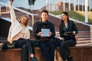 With ,notepad. Three young students are outside the university outdoors photo