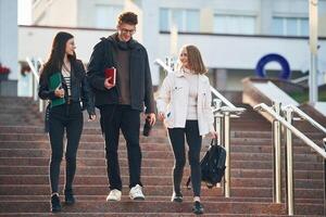 Going by the stairs.. Three young students are outside the university outdoors photo