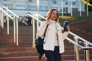 With ,water bottle. Young female student in casual clothes is outdoors photo