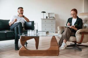 Man is on the therapy session with female psychologist photo