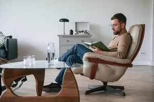 Male psychologist is sitting in the chair with notepad in the office photo