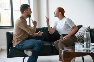 Side view of couple that are arguing. Sitting on sofa photo