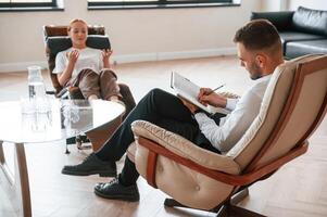 Woman ,is sitting in chair at an appointment with a psychologist photo