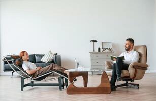 Side view. ..Woman is sitting in chair at an appointment with a psychologist photo