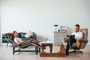 Side view. Woman is sitting in chair at,, an appointment with a psychologist photo