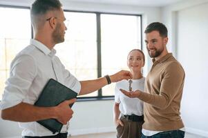 Giving,, the keys. Realtor shows an apartment to a young couple photo