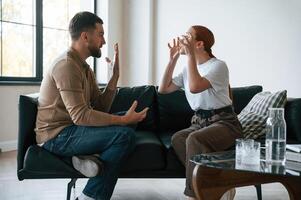 Side, view of couple that are arguing. Sitting on sofa photo