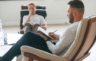 Woman, is sitting in chair at an appointment with a psychologist photo