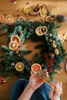 Decorator paints a fir cone with gold while sitting near the Christmas wreath. Cropped. Top view photo