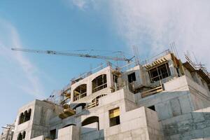Tower crane builds an apartment building against the sky photo