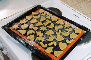 Unbaked gingerbread cookies stand on a baking sheet on the stove in the kitchen photo