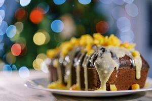 Glazed stollen with tangerine pieces stands on a plate on the table photo